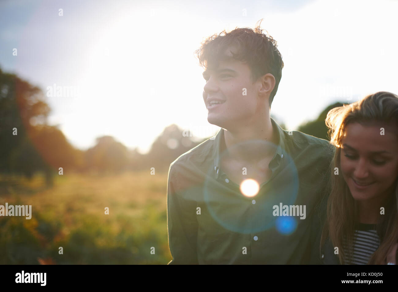 Feliz pareja joven paseando del brazo en el campo iluminado Foto de stock