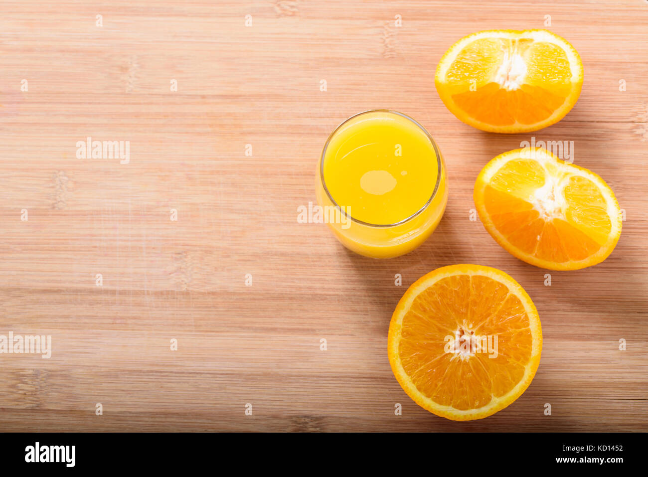 El jugo de naranja en vaso con rodajas de naranja sobre la tabla de cortar de madera Foto de stock
