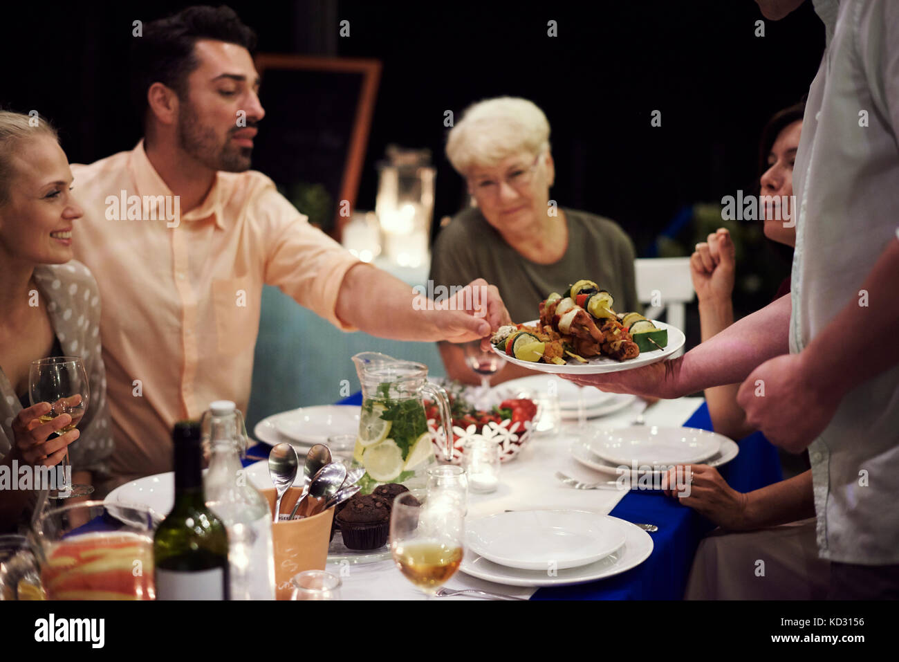 Grupo de gente sentada en la mesa, disfrutando de comida Foto de stock