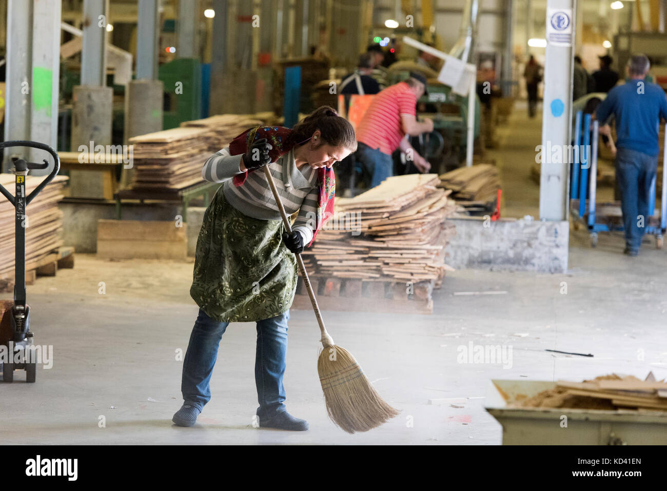 Mujer con la escoba para barrer el piso de la fábrica limpia Foto de stock