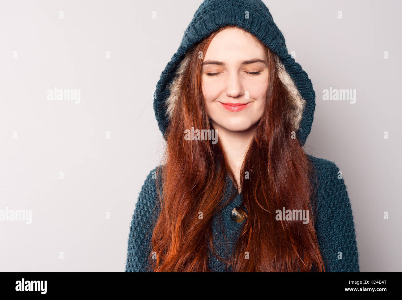 Una hermosa mujer alegre y con pelo largo vestido con un tejido cálido  azul-verde o chaqueta sudadera con capucha calentado con piel blanca. Ella  cerró los ojos Fotografía de stock - Alamy