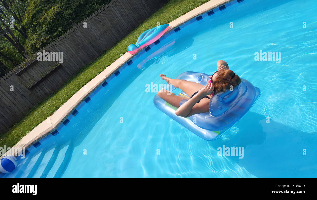 Mujer flotando en la piscina mirando al sol Foto de stock