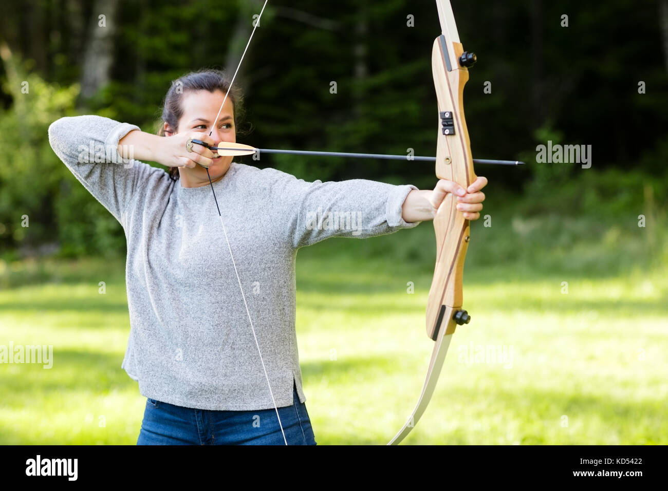 Seguro joven arquero apuntando con arco y flechas en el bosque Fotografía  de stock - Alamy