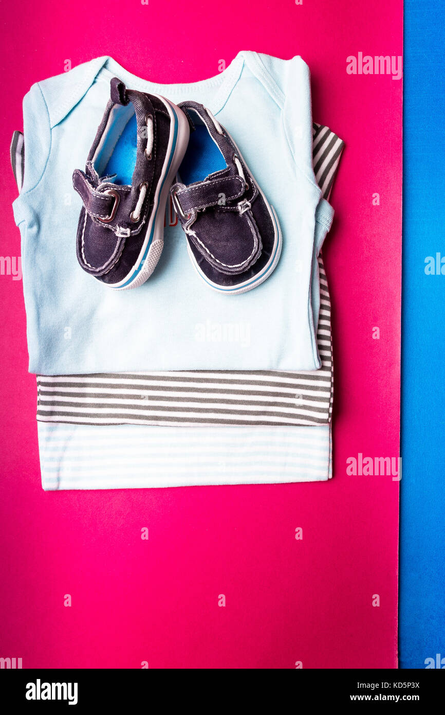 Bodysuit azul plegada con barco zapatos sobre fondo azul y rosa  minimalista. Pañal para recién nacidos. pila de ropa infantil. ropa infantil.  t Fotografía de stock - Alamy