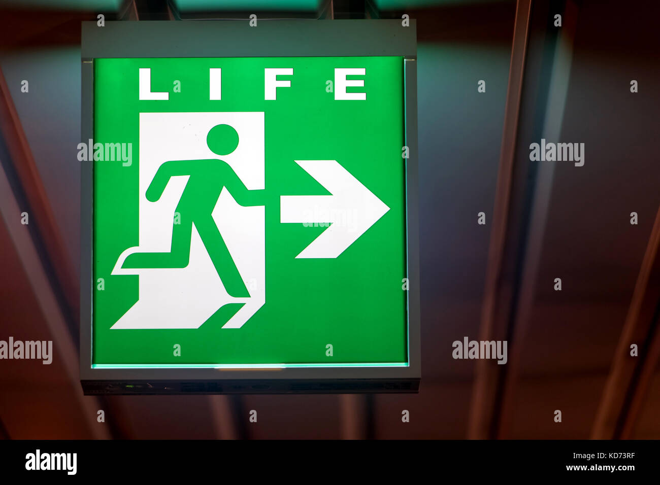 La señal de salida de emergencia indica el sentido de la vida. La junta de salida de emergencia se cuelga en el techo del edificio. Foto de stock