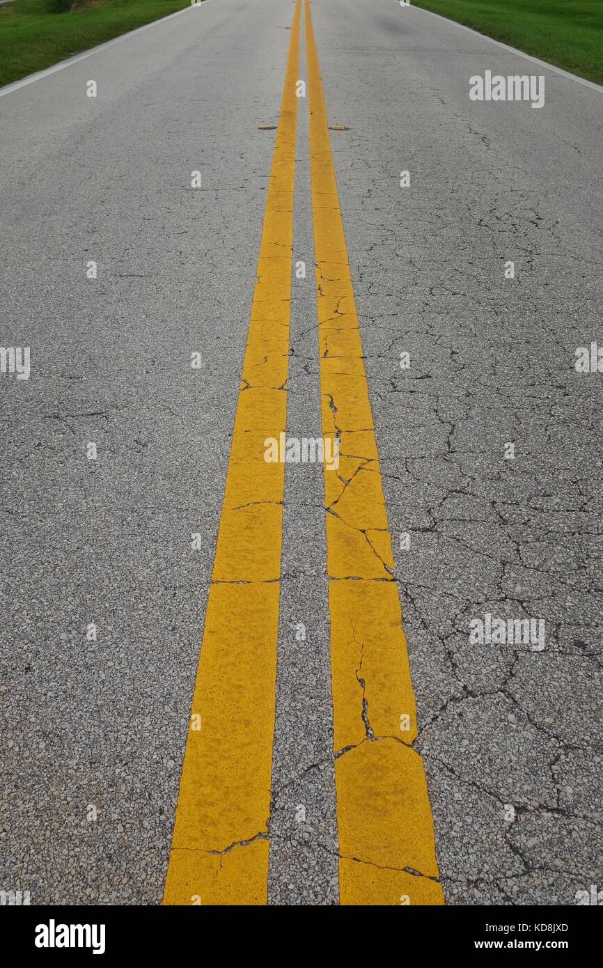 Doble amarilla de líneas centrales en una grieta en la superficie de la carretera en los EE.UU. Foto de stock