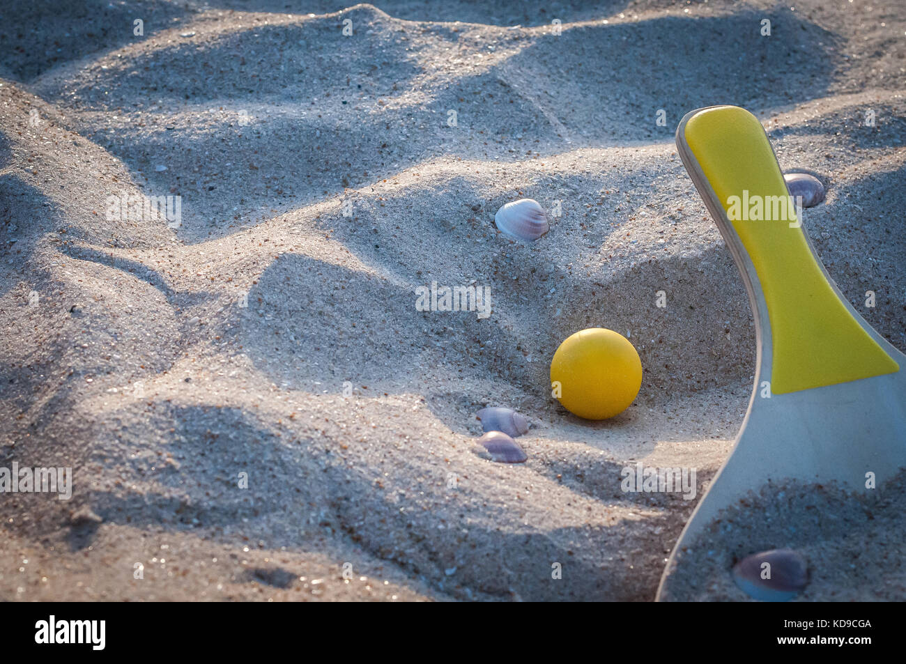 Pala de madera y una pelota amarilla en la playa Foto de stock