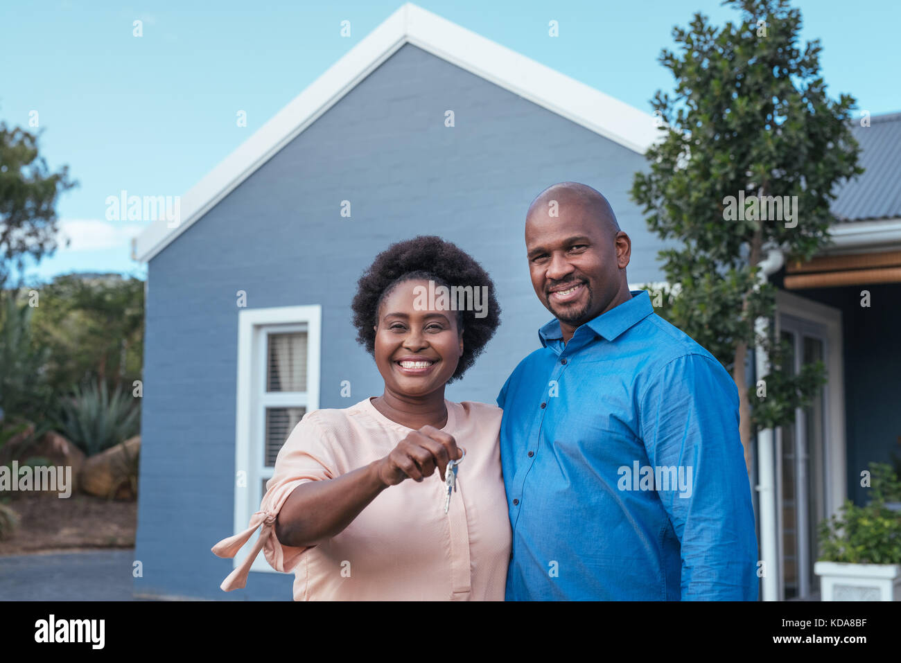 Sonriente pareja africana de pie con las llaves de su nuevo hogar. Foto de stock