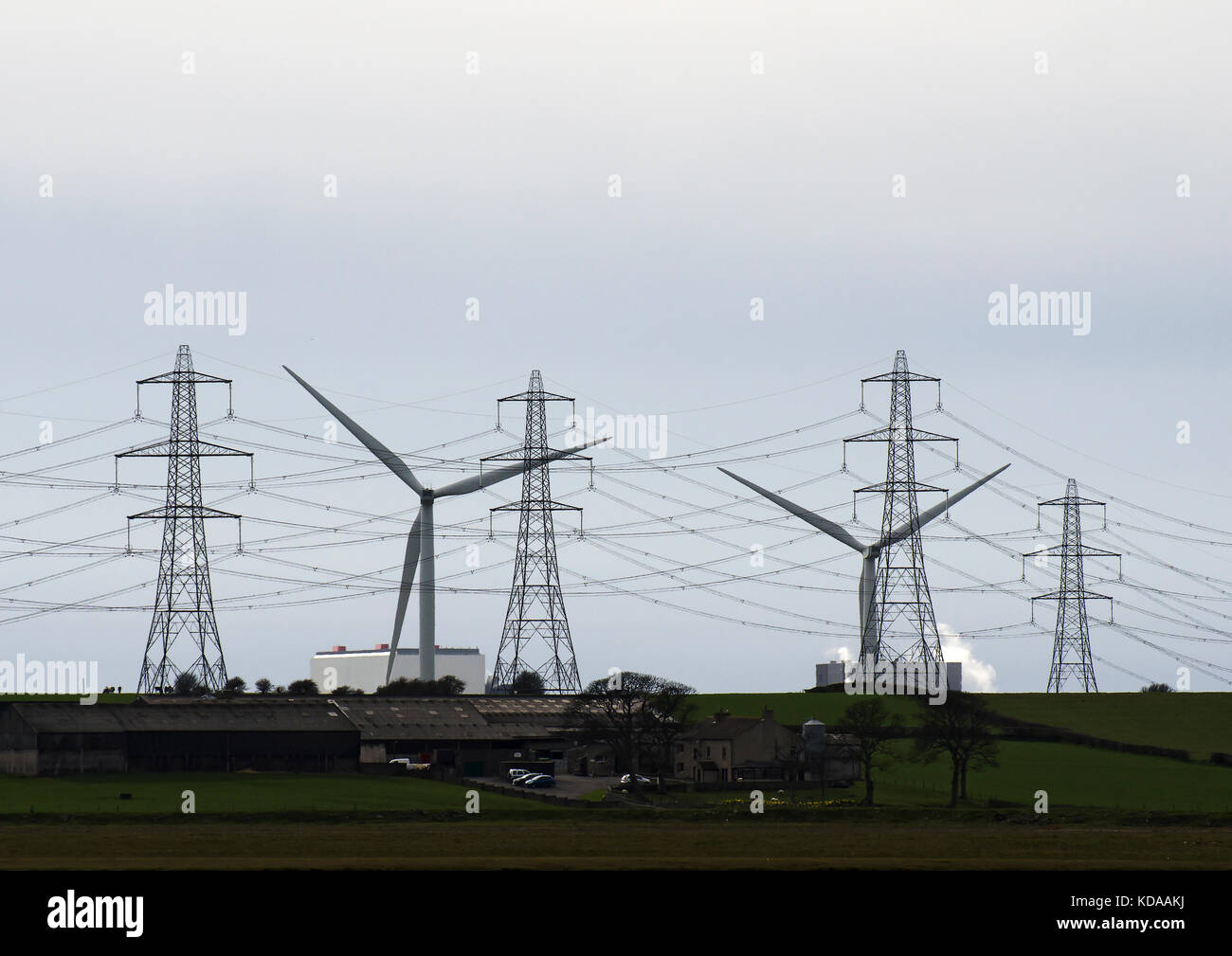Red nacional de líneas de transmisión de electricidad y los pilones delante de aerogeneradores en heysham, Lancashire, UK Foto de stock