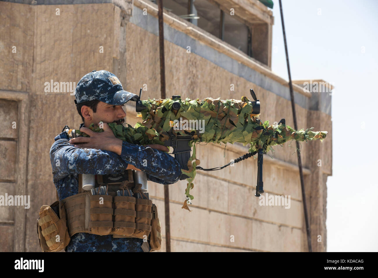 Un francotirador de la policía federal iraquí mira a través del alcance de su fusil en el techo de una patrulla de la base junio 29, 2017 en Mosul, Iraq. Ha habido un esfuerzo combinado entre las fuerzas estadounidenses e iraquíes en la zona para derrotar a los extremistas de Isis. Foto de stock