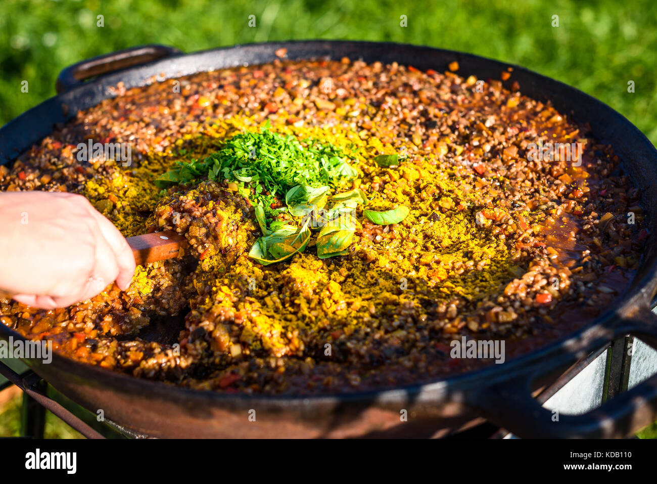 Cocinar y hacer la tradicional paella Española en hierro fundido de pan.  preparar paella grande al aire libre en el patio delantero de fiesta o  evento de negocios. cate profesional Fotografía de