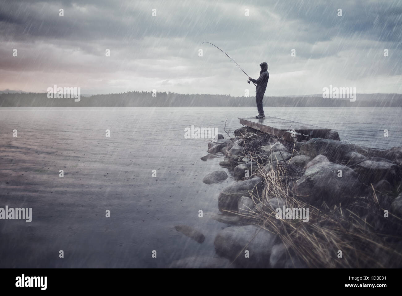 Hombre en un lago de pesca en la lluvia Foto de stock