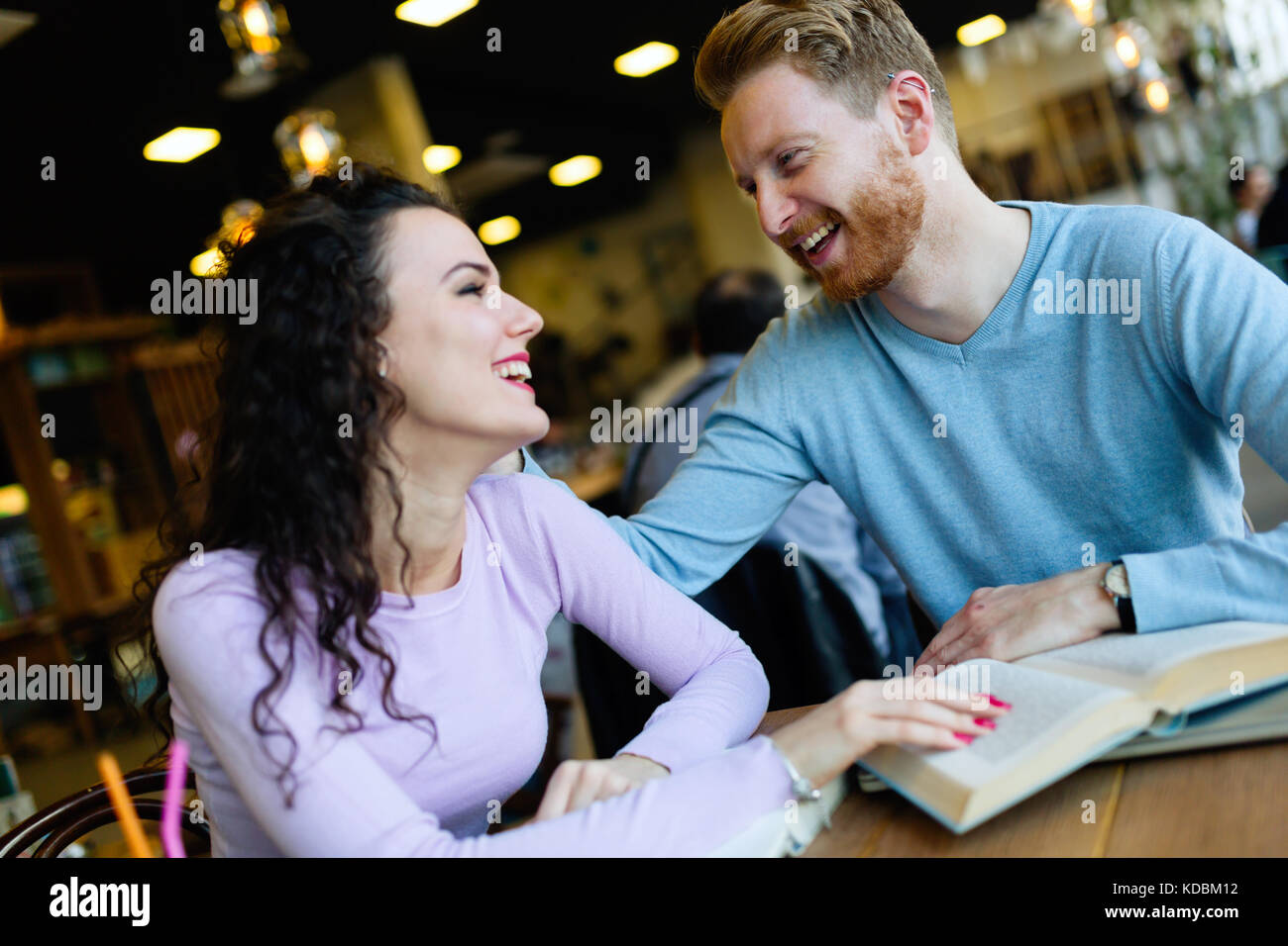 Los jóvenes estudiantes dedicar tiempo a la lectura de libros en la cafetería. Foto de stock