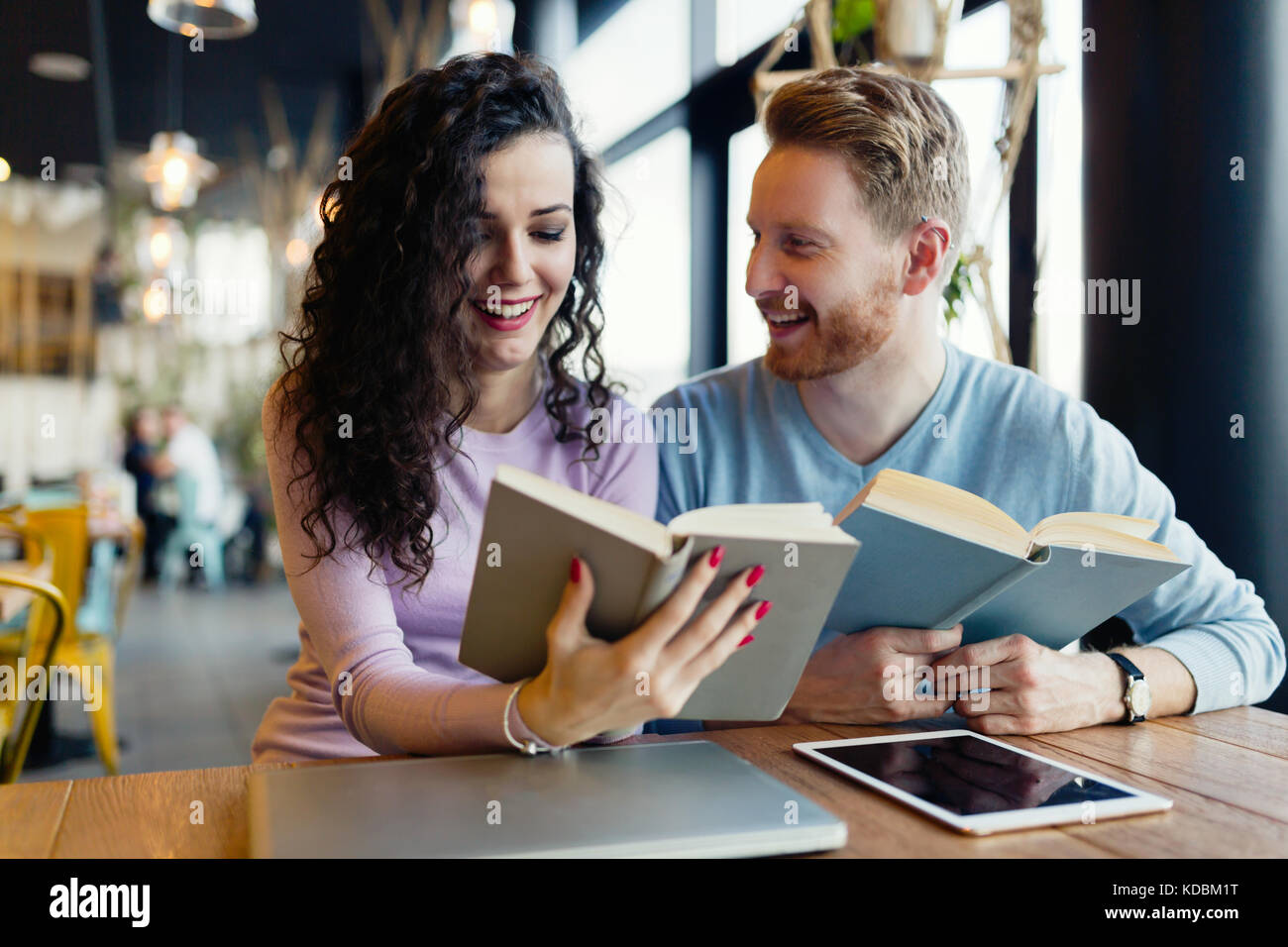 Los jóvenes estudiantes dedicar tiempo a la lectura de libros en la cafetería. Foto de stock