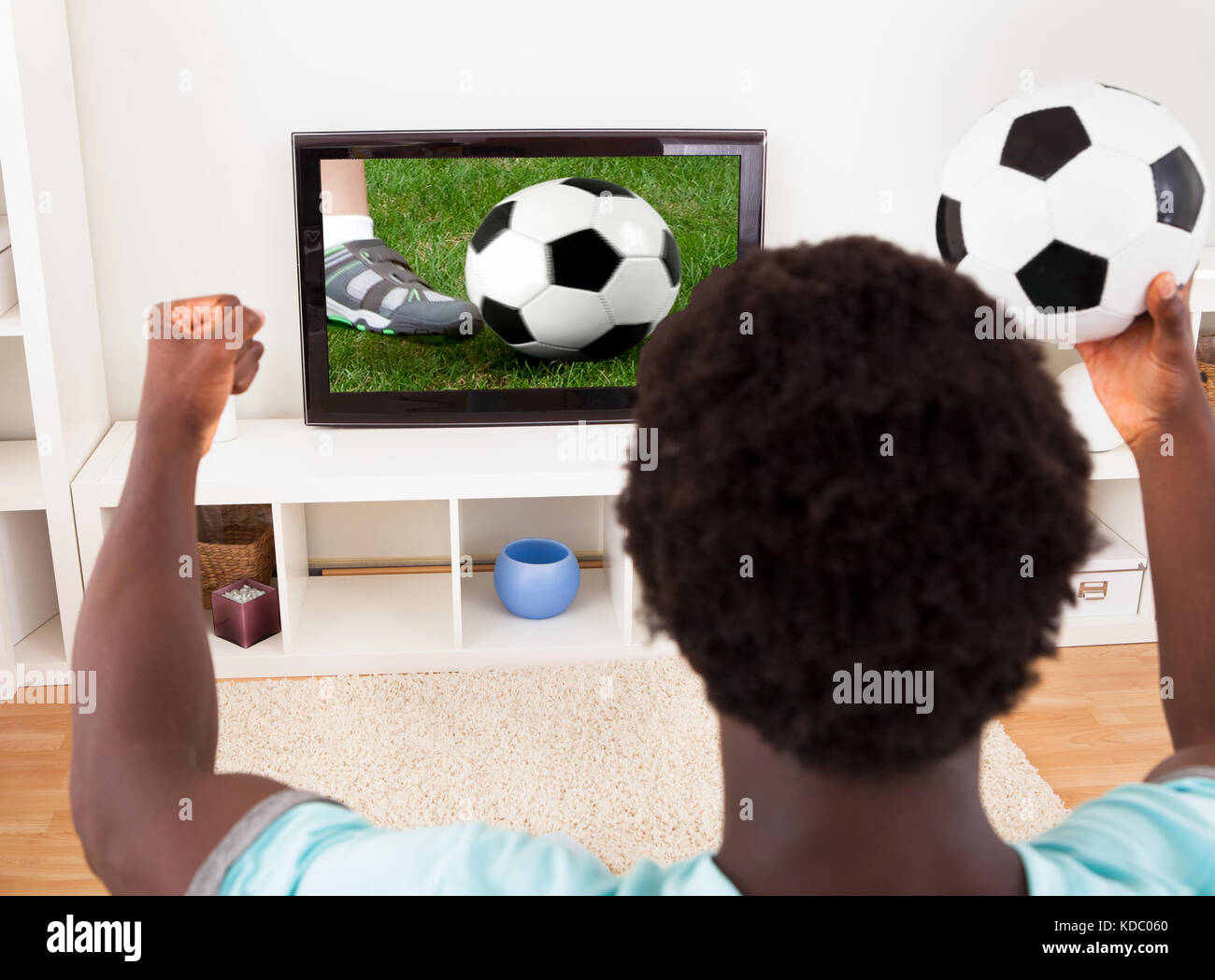 Feliz joven africana viendo partido de fútbol en la televisión en casa Foto de stock