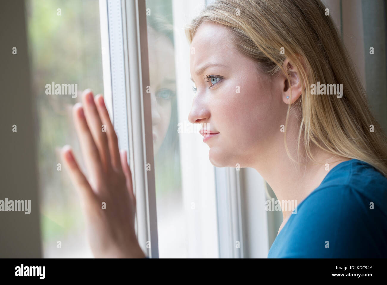Triste Joven sufre depresión mirando afuera de la ventana Foto de stock