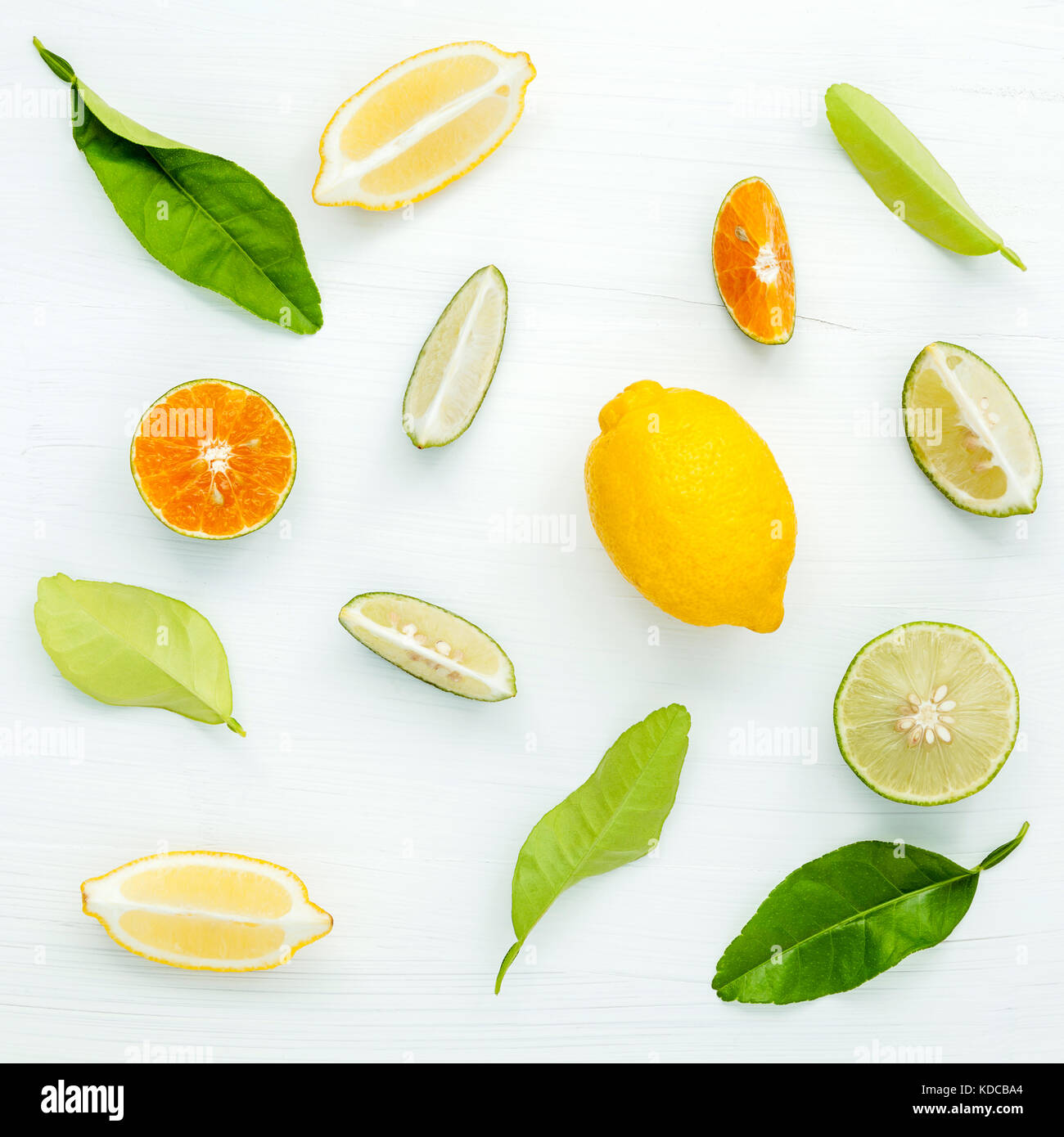 Los cítricos frescos mixtos y fondo de hojas. limones frescos, rodaja de limón ,limón y naranja sobre mesa de madera blanca con laicos plana. Foto de stock