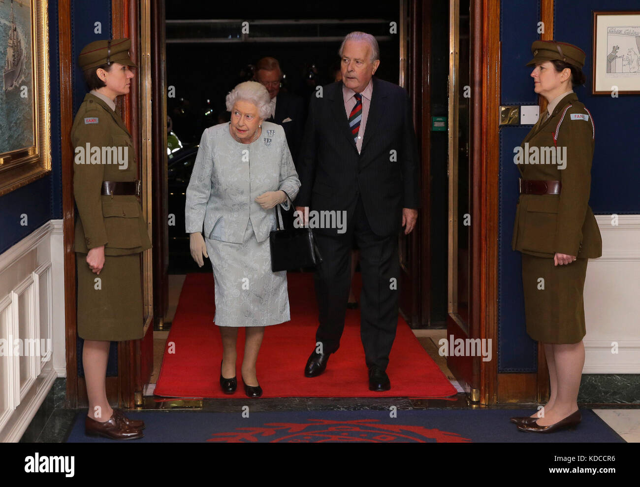 La reina Elizabeth II, acompañada por el coronel Ian Paterson, camina por dos mujeres vestidas como Yeomanry de primeros auxilios de la era de la Segunda Guerra Mundial durante una recepción en el Club del Ejército y la Marina en el centro de Londres, para conmemorar el centenario del Servicio de la Marina Real de Mujeres y de la Corporación del Ejército Auxiliar de Mujeres Foto de stock