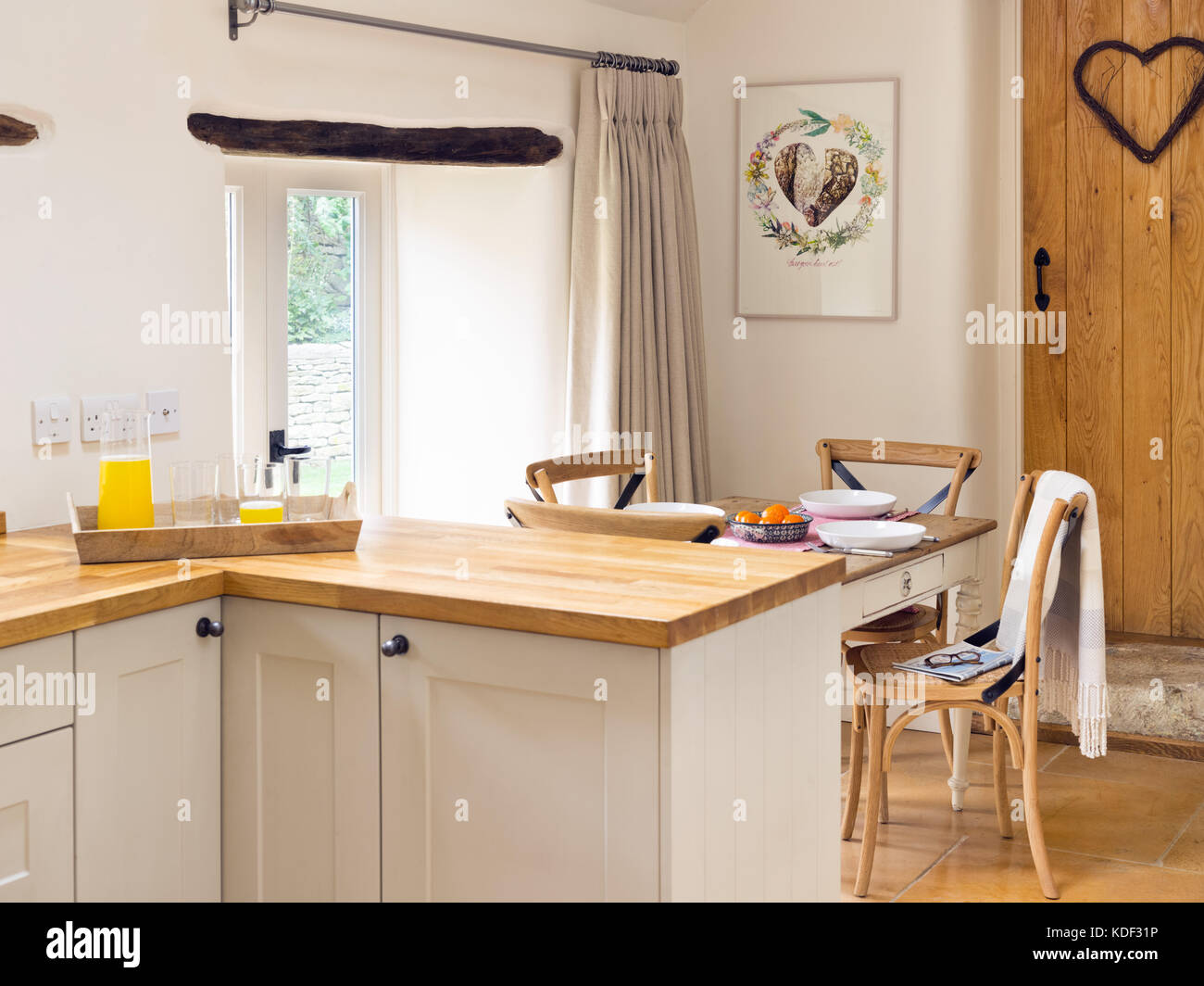 Una cocina comedor, mostrando crema estilo shaker, armarios de madera maciza y encimera de cocina pequeña tabla. Foto de stock