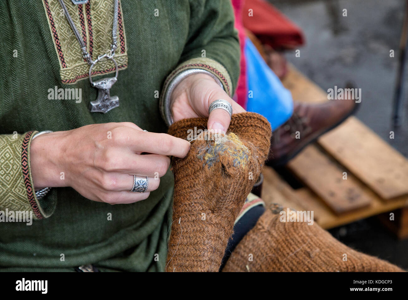 Persona medieval remendando calcetines de lana en una feria. Recorta shot mostrando las manos con calcetines de lana arreglando. Foto de stock