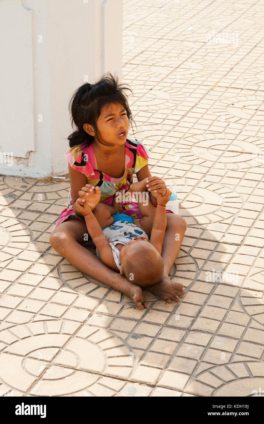 Phnom Penh, Camboya - Febrero 21, 2013: un niño no identificado con un bebé no identificado sentarse pidiendo limosna en las calles de Phnom Penh Foto de stock
