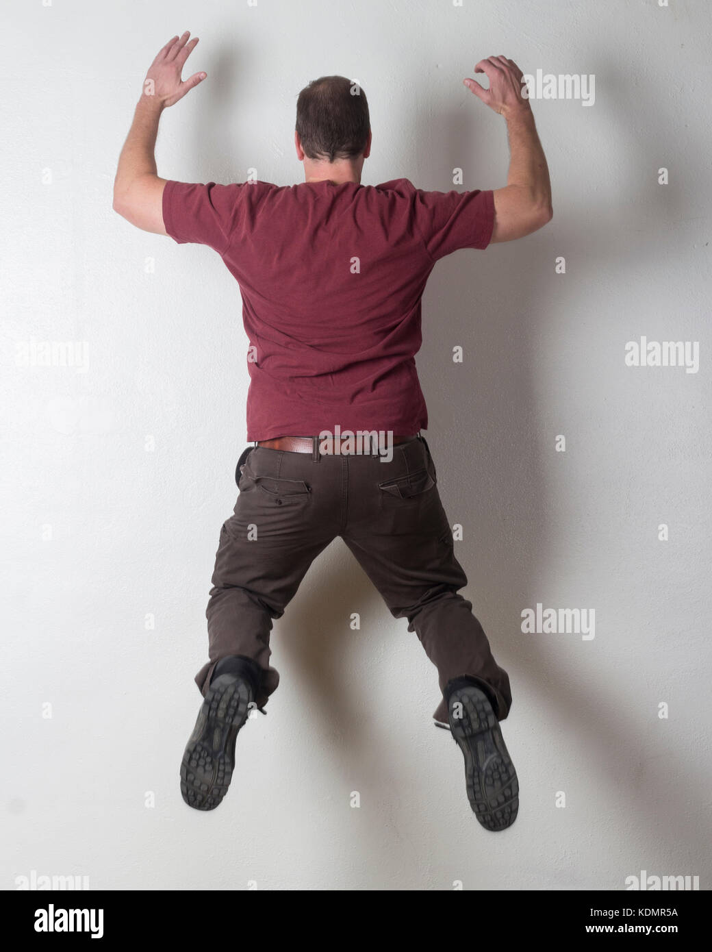 Hombre saltando contra una pared blanca. Foto de stock