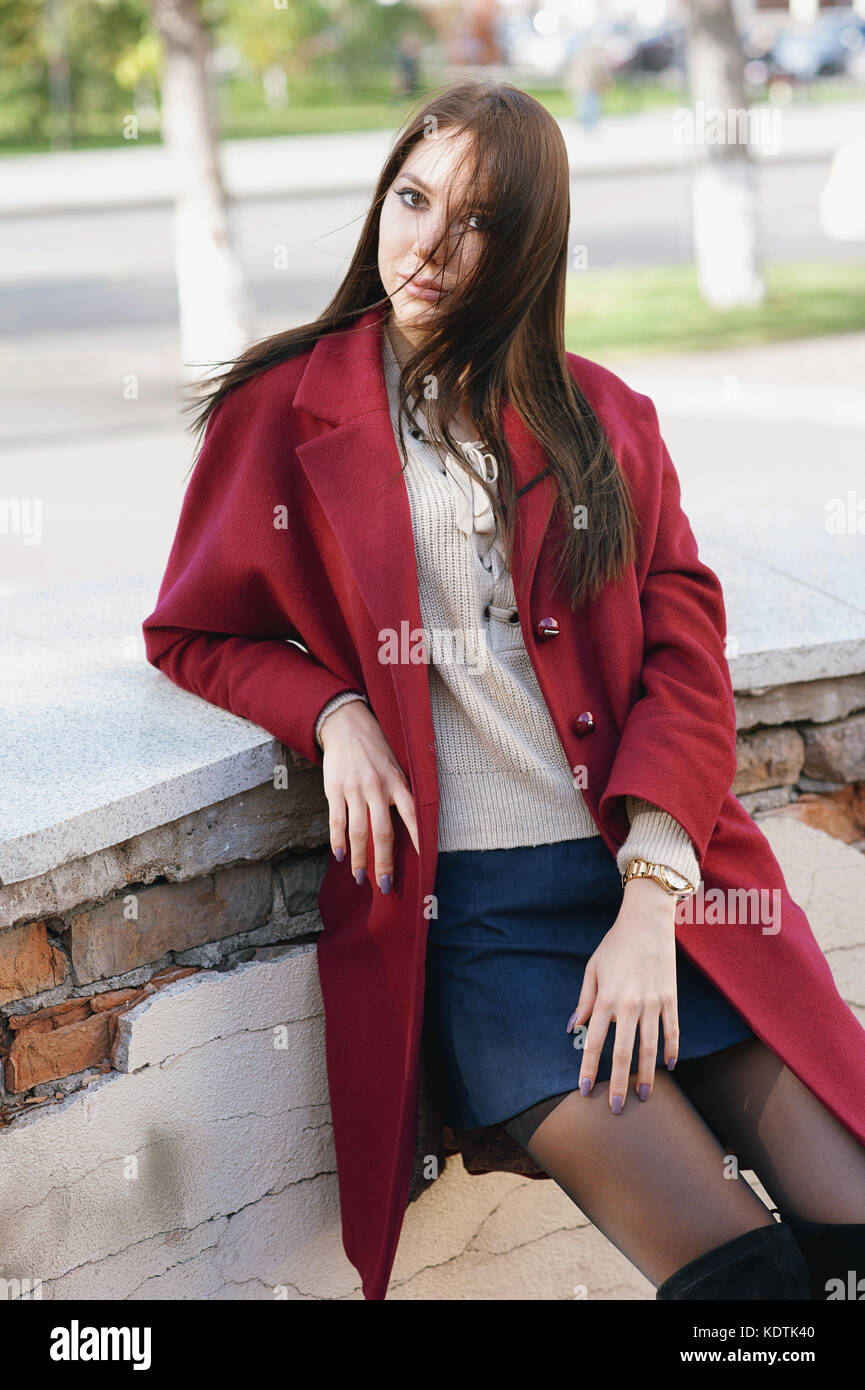 joven mujer elegante en Borgoña abrigos, street style, tendencias, primavera y otoño falda oscuro, flirty mira, el pelo en el viento Fotografía de stock - Alamy