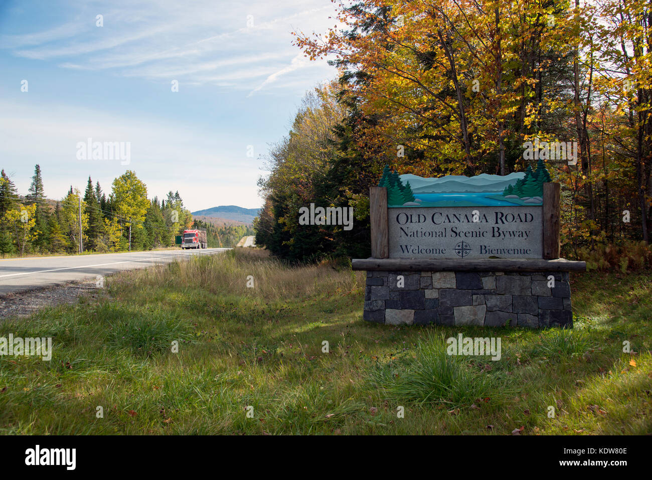 Firmar para el viejo Canadá National Scenic Road, una desviación en el norte de Maine al sur de la frontera con Quebec, con camión de registro en segundo plano. Foto de stock