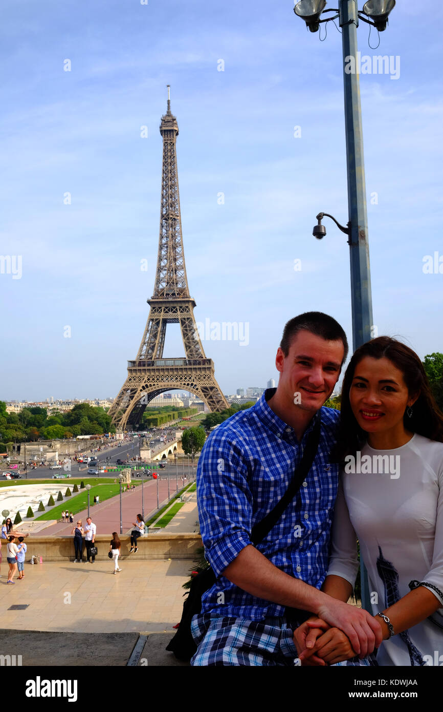 Una joven pareja posar delante de la Torre Eiffel en Paris Foto de stock