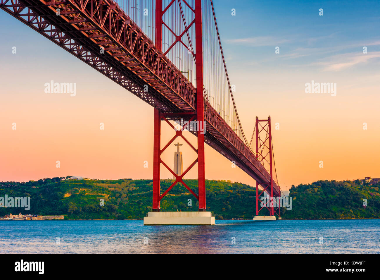 Puente 25 de abril, el río Tajo y la estatua de Cristo Rey en Lisboa, en Portugal, alrededor de la puesta del sol Foto de stock
