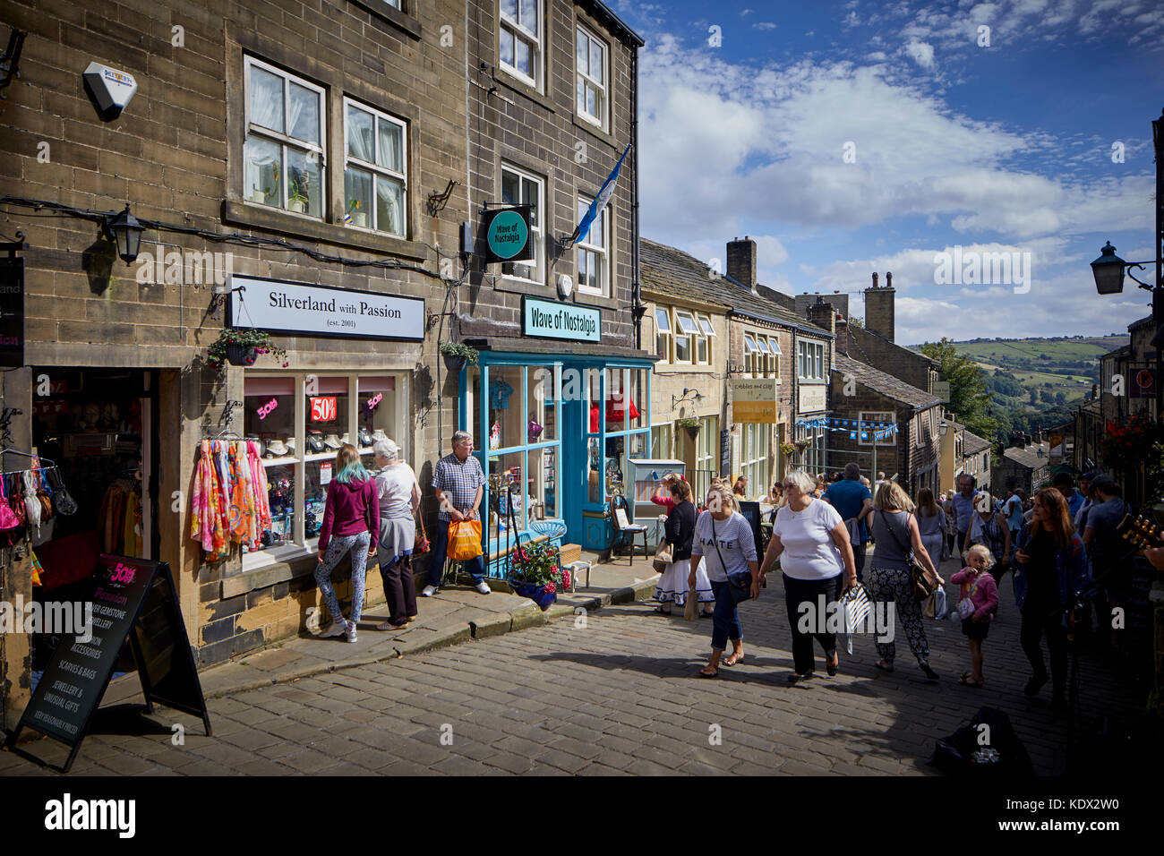 Los Peninos village, Haworth en West Yorkshire, Inglaterra. terrazas de casas y negocios en la empinada calle principal Foto de stock