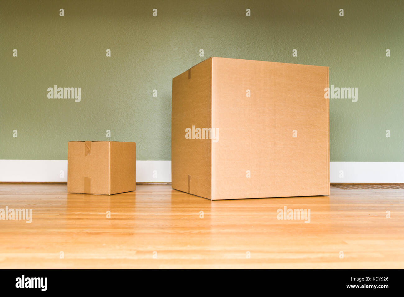 Una caja de cartón Sall, junto a un cuadro grande sobre un piso de madera. Foto de stock