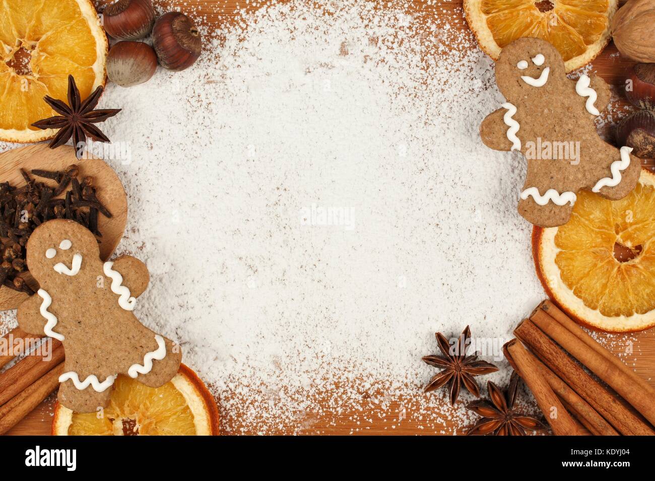 Hornear vacaciones marco temático con hombres de pan de jengibre, nueces y especias sobre un fondo de azúcar en polvo Foto de stock