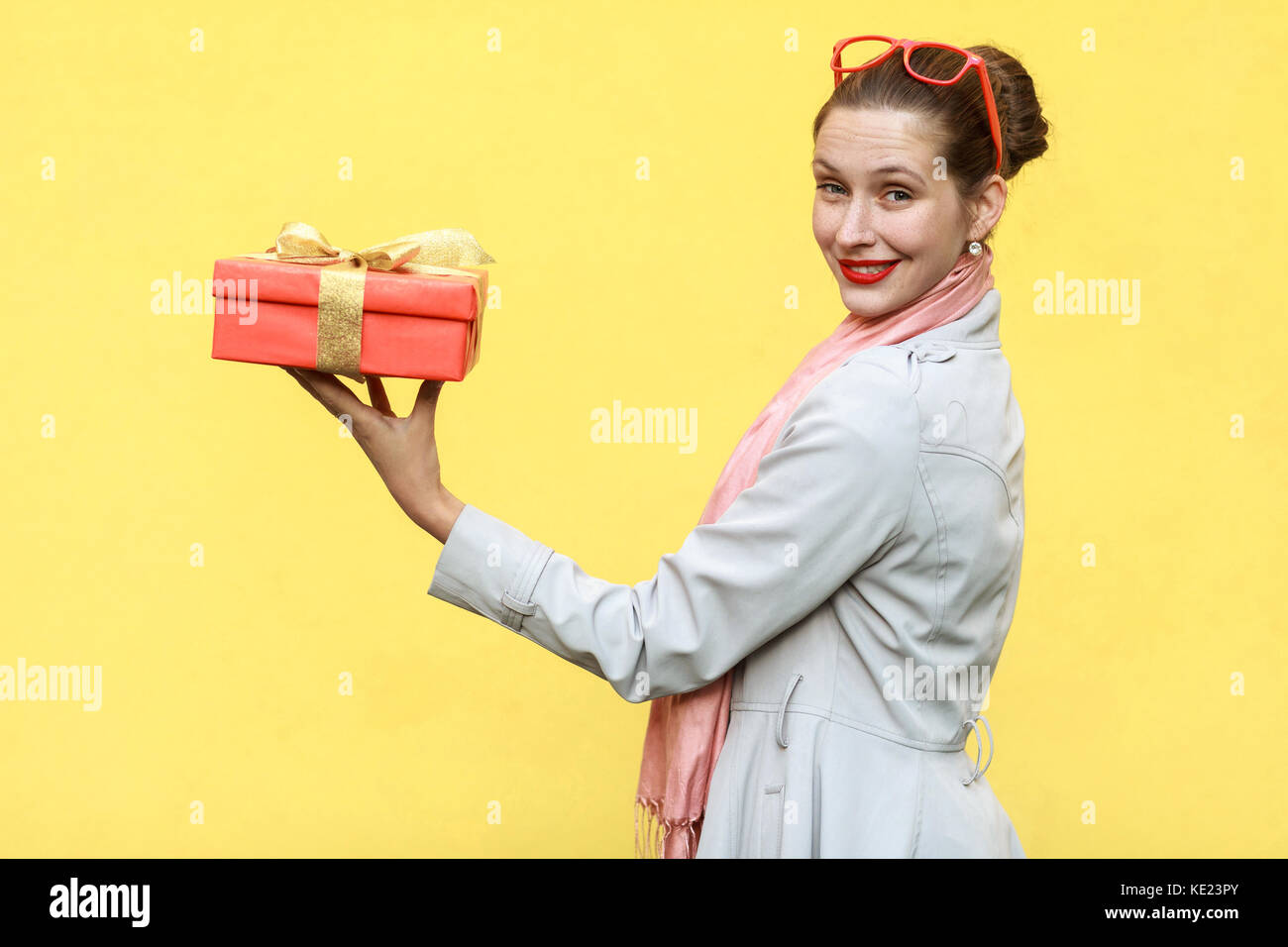 Regalo con amor. interesante jengibre joven mujer adulta con una caja de regalo sobre fondo amarillo. Foto de estudio Foto de stock