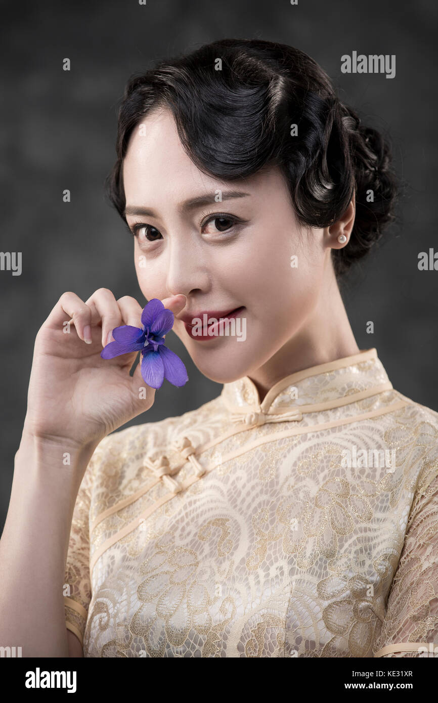 Retrato de joven mujer sonriente en estilo retro ropa oriental posando con flor Foto de stock