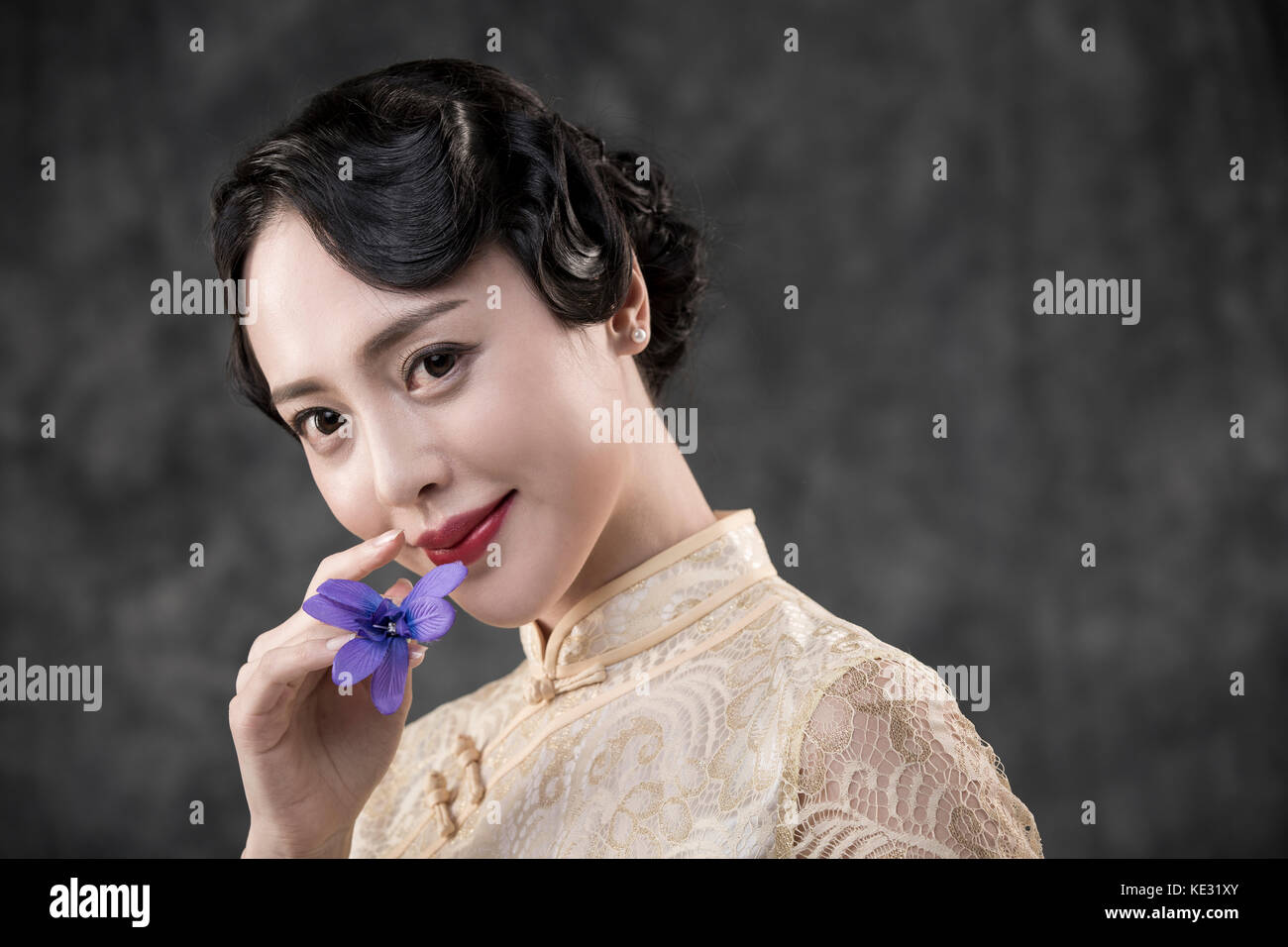 Retrato de joven mujer sonriente en estilo retro ropa oriental posando con flor Foto de stock
