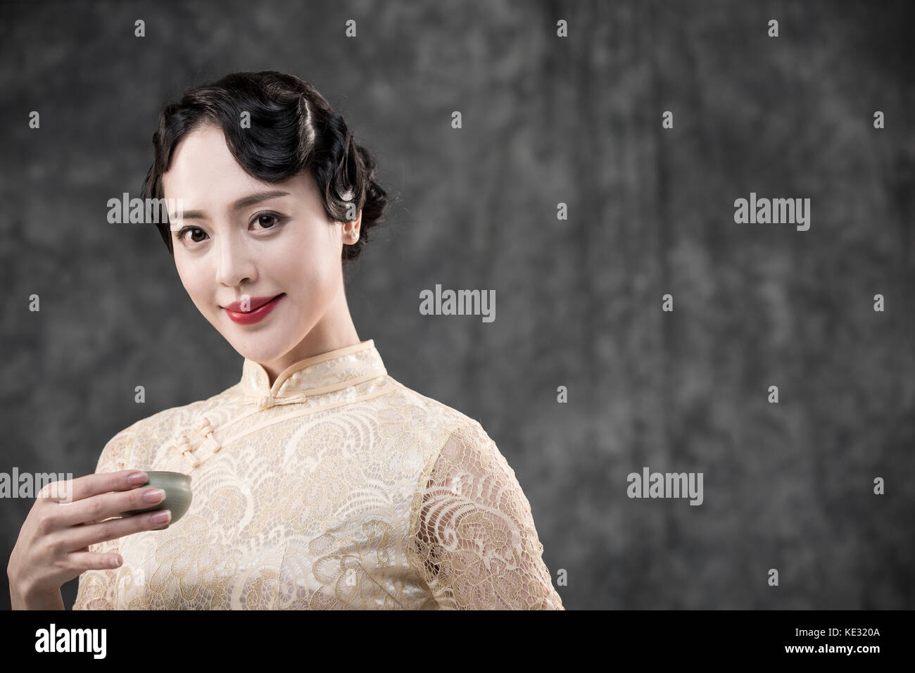Retrato de joven mujer sonriente en estilo retro ropa oriental posando con vaso Foto de stock