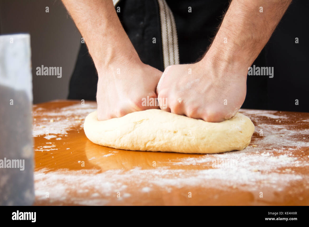 Baker macho amasar la masa sobre una mesa recubierta de harina Foto de stock