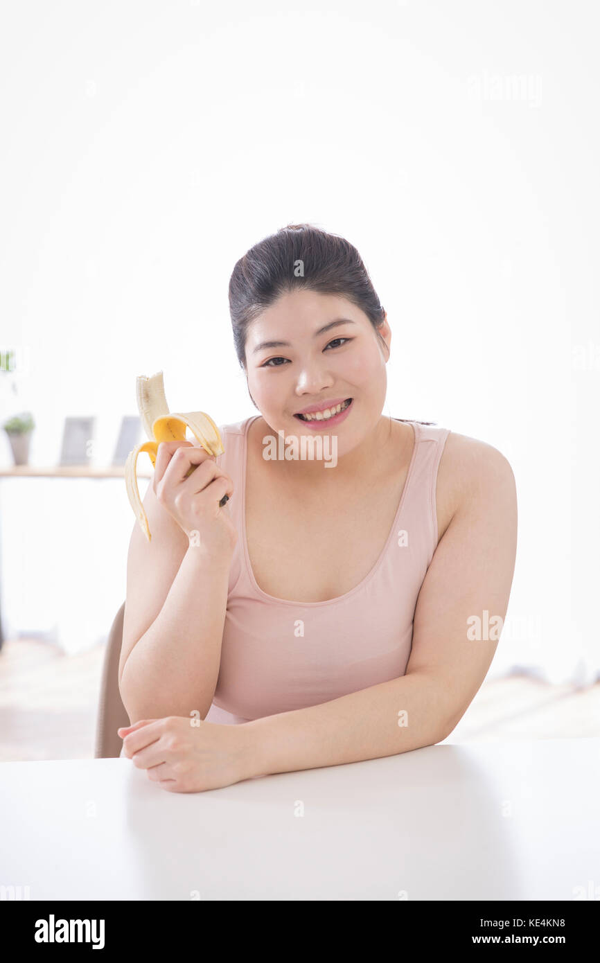 Retrato de joven mujer sonriente con plátano posando Foto de stock