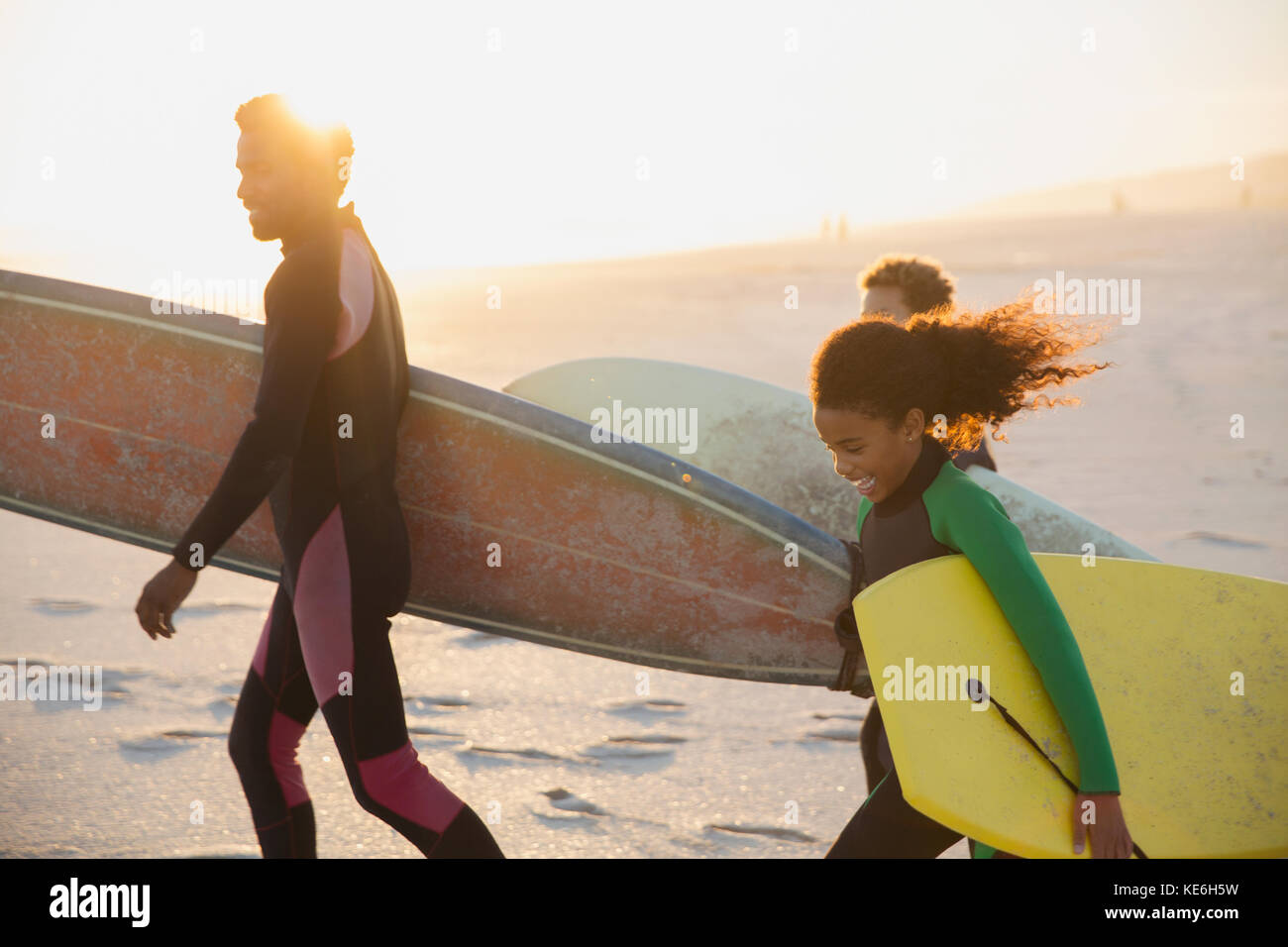 Familia llevando tablas de surf y tablas de boogie en la soleada playa