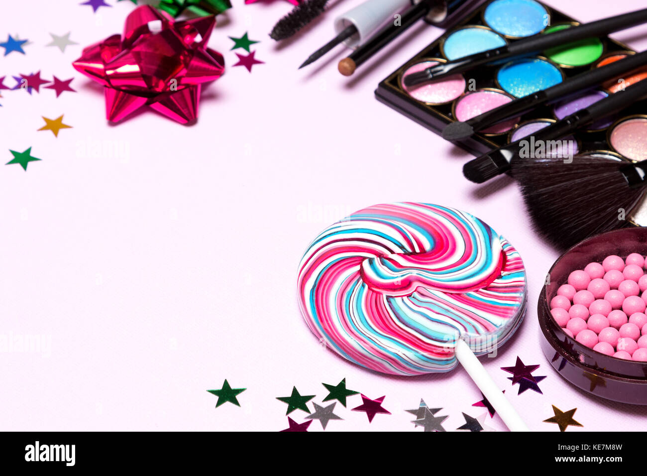 Los cosméticos decorativos para el maquillaje de fiesta. blush, color glitter sombreador de ojos, delineador de ojos líquido, mascara, pinceles con lollipop, confeti y don wra Foto de stock