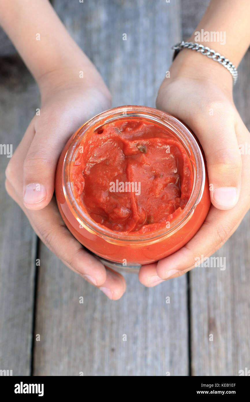 Mano sujetando la lasaña la salsa en una jarra Foto de stock