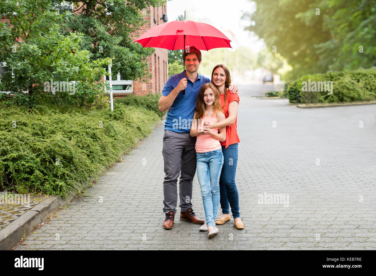Retrato de una pareja joven con su hija la celebración de paraguas Foto de stock
