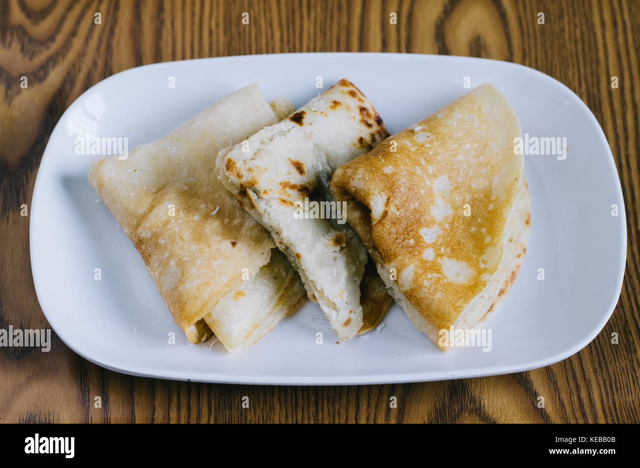 Pancake plegada en un plato sobre un fondo de madera. malaya llamado 'lempeng' Foto de stock