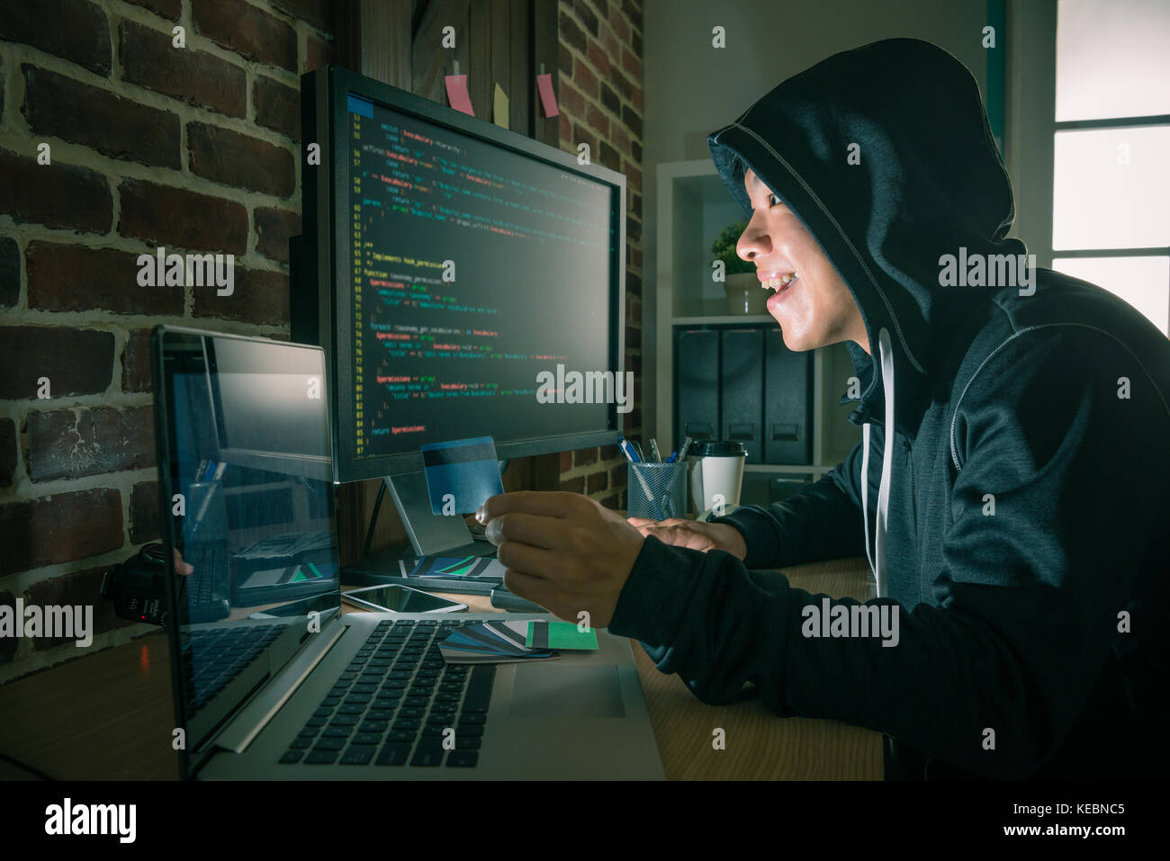 Programador joven alegre hombre utilizando código idioma sistema robar información de tarjetas de crédito y haciendo fraude crímenes por cuenta. Foto de stock