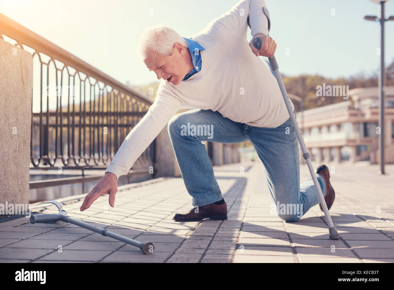 Hombre de edad alcanzando muleta mientras intentaba subir Foto de stock