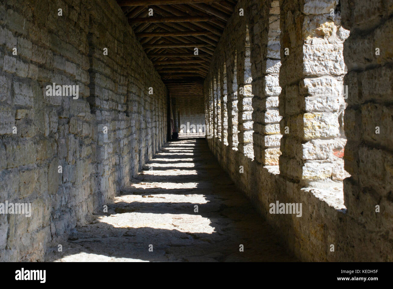 Una galería de columnas de piedra de la antigua fortaleza. Juego de luz y sombra. Foto de stock