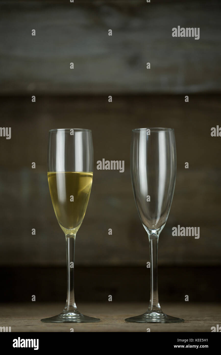 Lleno y vacío, una copa de champán a la superficie de madera Foto de stock