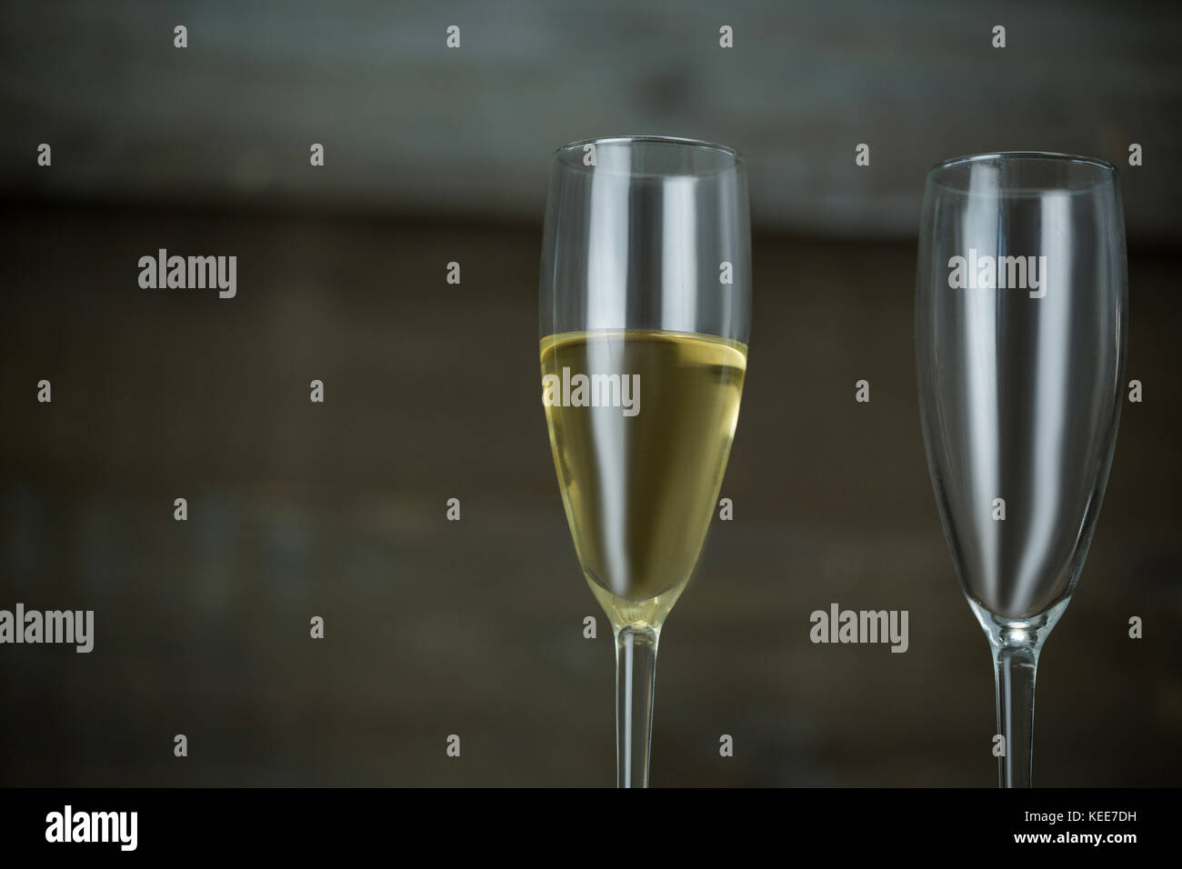Lleno y vacío vaso de champán contra el fondo de madera Foto de stock