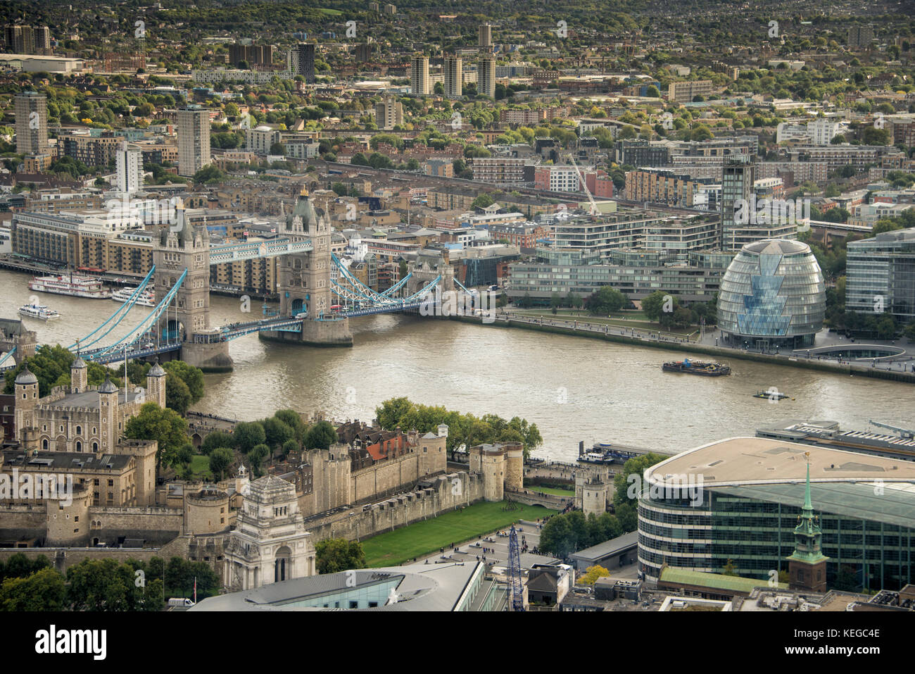 Vista desde arriba a través de los tejados de Londres hacia la Torre de Londres y el Tower Bridge y cruzando el río Támesis hasta el Sureste de Londres Foto de stock